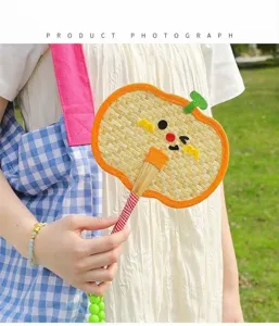 Hand-woven pumpkin shaped palm leaf fan used as a decorative charm pendant for bags