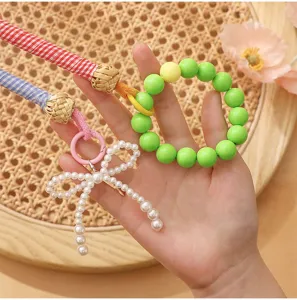 Hand-woven checkered straps with green beaded loop and a delicate pearl bow charm detail