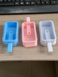 Close-up view of three colorful silicone popsicle molds featuring clear lids on a wooden desk