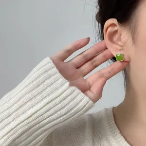 Close-up of model wearing vintage green square stud earrings with gold trim