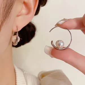 Close-up of elegant silver hoop earrings with a large white pearl detail