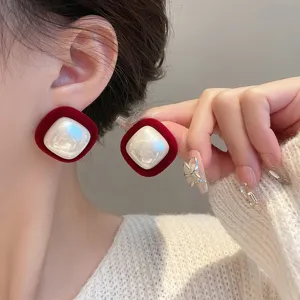 Macro view of red velvet square earrings featuring a lustrous white pearl center