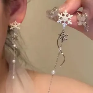 Close-up of long white snowflake earrings featuring delicate tassels and pearl accents