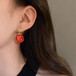 Detailed shot of a red and gold dragon character drop earring worn by an Asian model