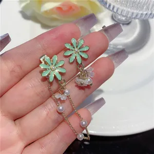 Detailed view of green daisy drop earrings with pearls and long gold-tone chains.