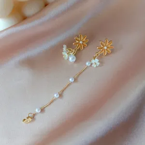 Detail view of asymmetrical flower earrings with pearls and gold floral design