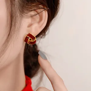 Macro detail of elegant vintage-style red and gold knot stud earrings worn on model's ear