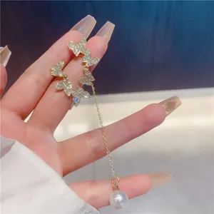 Close-up of elegant butterfly earrings with rhinestone wings and pearl drop chain