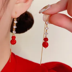 Detailed view of elegant long gold tassel earrings with red berry beads and crystals