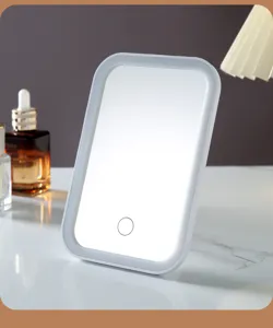 Detail shot of lit LED makeup mirror on marble vanity table with skincare props