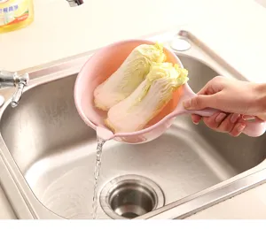 Nahaufnahme eines rosa Wasserschöpfers aus Kunststoff zum Waschen von Gemüse in der Spüle