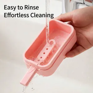 Pink silicone ice pop mold being rinsed under water for easy cleaning.