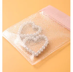 Macro view of a textured transparent EVA jewelry storage bag featuring a pink sealing strip