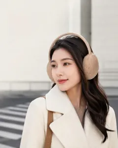 Detail showing a woman wearing warm beige plush earmuffs in an elegant outdoor view