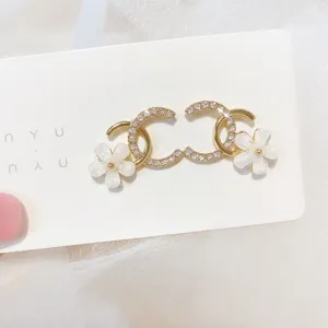 Detail view of crystal-encrusted double C earrings with delicate white flower charms