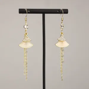 Detailed view of elegant gold fan-shaped dangle earrings with sparkling rhinestones and cream enamel