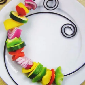 Detailansicht eines schwarzen spiralförmigen antihaftbeschichteten Grillspießes mit Gemüse