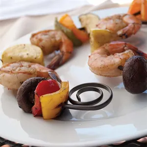 Nahaufnahme von runden Grillspießen mit Garnelen und Gemüse auf einem weißen Teller
