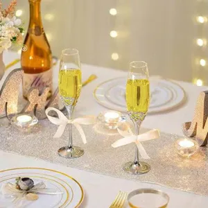 Detailaufnahme von Kristall-Champagnergläsern mit Strassstielen und eleganten Schleifen.