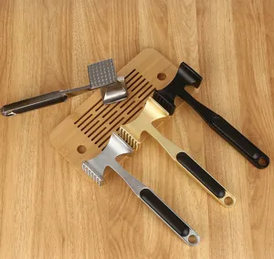 Detailansicht der doppelseitigen Fleischklopfer in Silber, Gold und Schwarz auf Holz