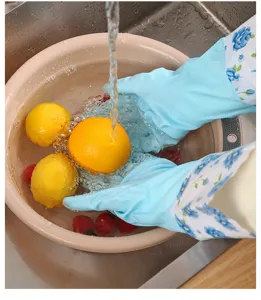 Gants de ménage en caoutchouc bleu imperméables lavant des fruits dans un évier de cuisine