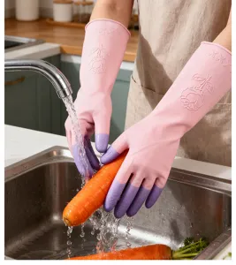 Détail de gants de vaisselle en latex imperméables rose et violet lavant des carottes