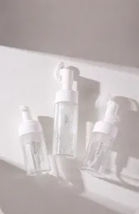 Detailweergave van drie heldere schuimpompflessen met witte pompen op witte achtergrond.