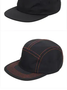 Detail view of 5-panel camper hats featuring tonal black and vibrant orange contrast stitching.