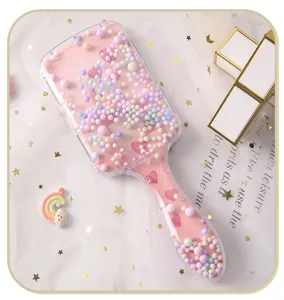 Detalle de espejo de maquillaje portátil con estampado de corazones y mango de arena movediza
