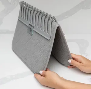 Detalle de una alfombrilla de secado gris plegable con rejilla extraíble para la cocina