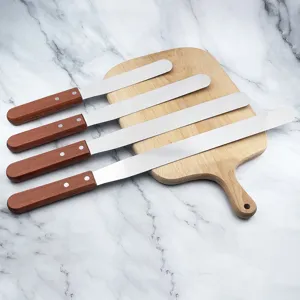 Set of 4 stainless steel cake spatulas with wooden handles on a cutting board for baking decor