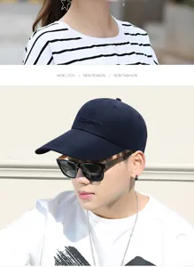 Detail view of navy blue baseball cap with embroidered letter design on Asian model