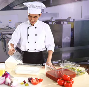 Gros plan d'un chef utilisant des bacs PC transparents de qualité alimentaire en cuisine.