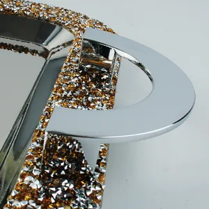 Close-up detail of luxurious stainless steel serving tray with amber crystal border and handle