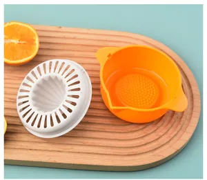 Close-up of a manual plastic citrus juicer with white reamer and orange base container.