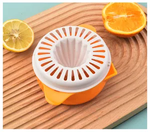 Manual plastic citrus juicer with orange and lemon slices on a wooden board