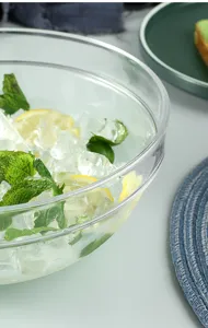 Detail of a large clear acrylic salad bowl with ice, lemon slices and mint leaves
