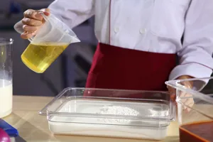 Chef utilisant un bac alimentaire PC transparent pour mélanger ingrédients en cuisine.