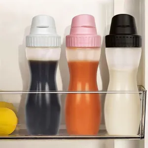 Juego de tres botellas de salsa de cocina con tapas grises rosas y negras en la nevera