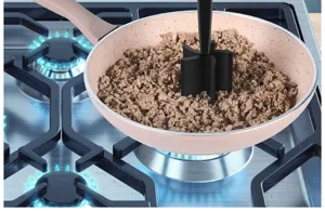 Detail view of the black meat chopper tool in use, stirring minced meat inside a pan.