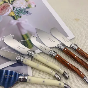 Detailansicht eines Laguiole Käsemesser-Sets mit cremefarbenen und Holz-Griffen