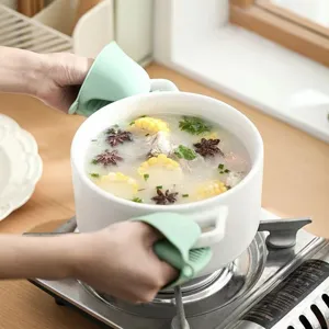 Vue détaillée de maniques en silicone vert résistant à la chaleur soulevant un pot