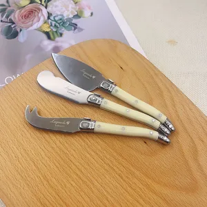 3-piece Laguiole style cheese knife set with cream handles on wood