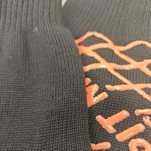 Detalle de guante negro resistente al calor con silicona naranja antideslizante