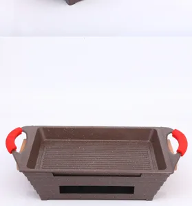 Detail van een rechthoekige Maifan stenen grillpan met rode hittebestendige siliconen grepen