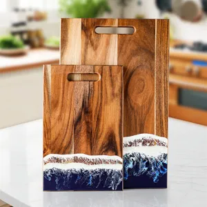 Handcrafted acacia wood cutting board set with decorative blue ocean wave resin design