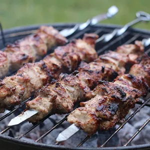 Detail view of 45cm stainless steel flat skewers with seasoned meat grilling on a BBQ