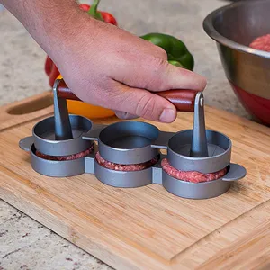 Action shot of a manual 3-hole slider burger press molding meat on a wooden board