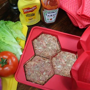 Detailansicht der roten Silikon-Burgerpresse für hexagonale Fleischpastetchen im Einsatz