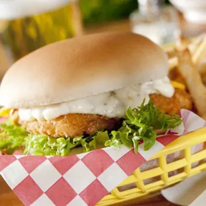 Detail of a yellow plastic fast food basket with red checkered paper serving a burger